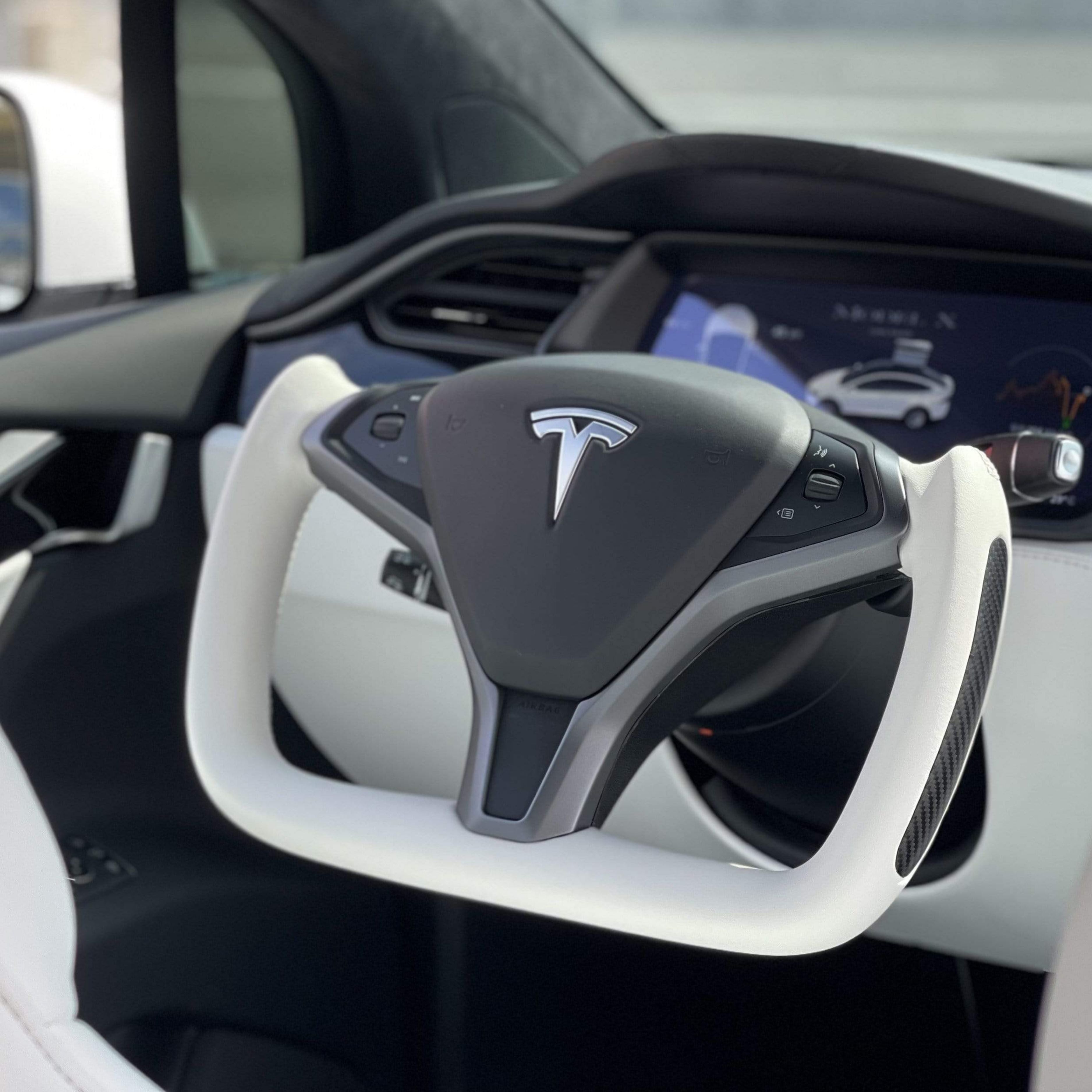 White Leather yoke steering wheel option installed with the original Tesla center airbag and controls