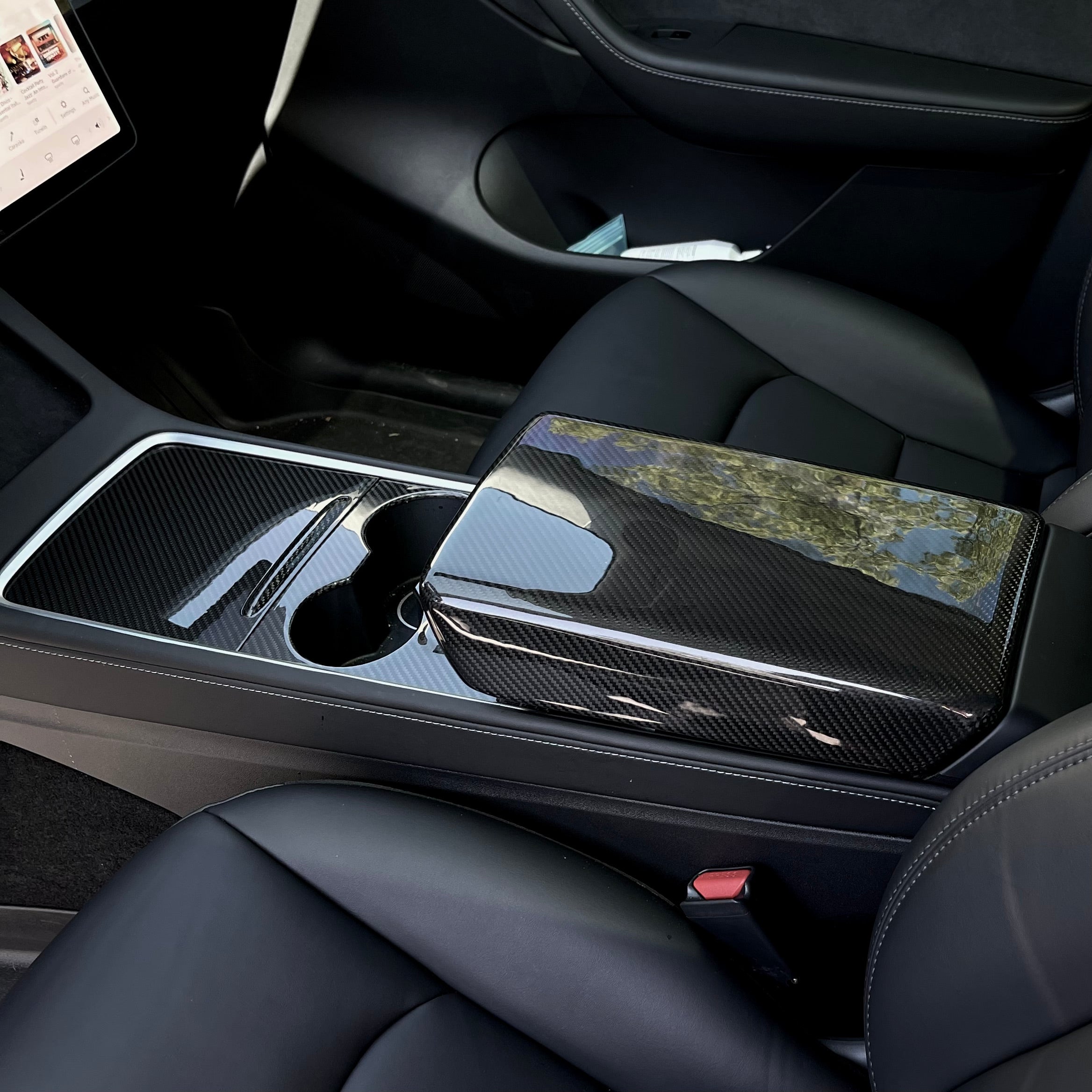Glossy carbon fiber armrest shell installed over the center-console lid