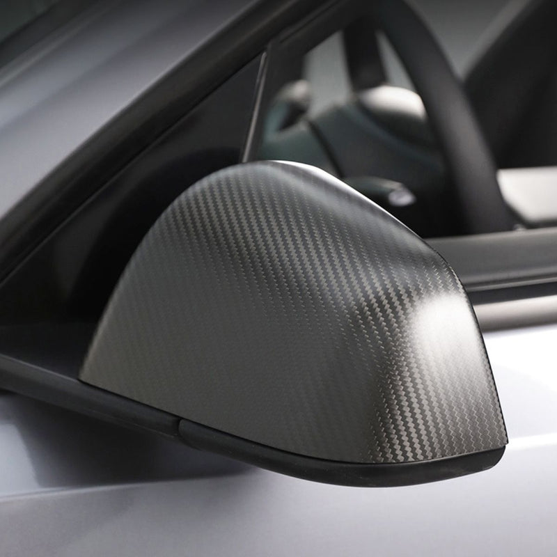 Matte carbon fiber mirror overlay installed over an original Tesla mirror cap
