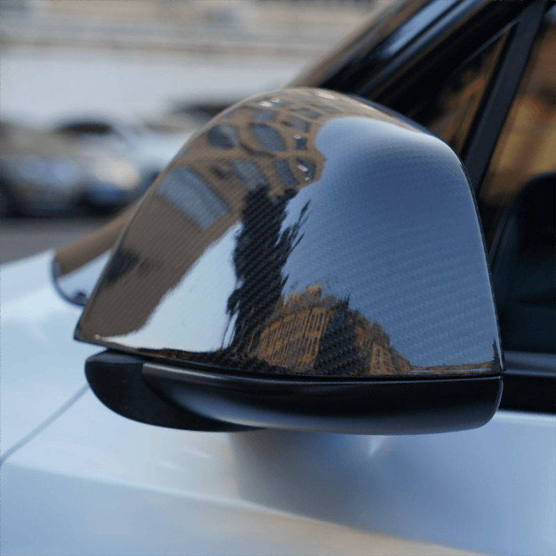 Glossy carbon fiber side mirror overlay showing reflected light